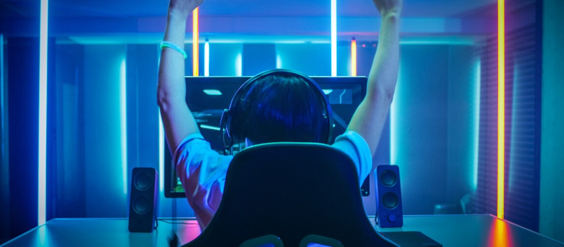 Young person sitting in gaming chair in front of computer with head phones on