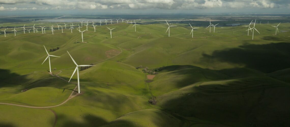 Windmills across a green landscape with clouds in the background